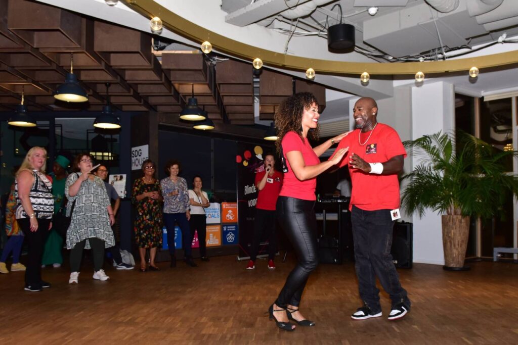 twee salsadansers dansen samen met personen op de achtergrond die naar ze kijken