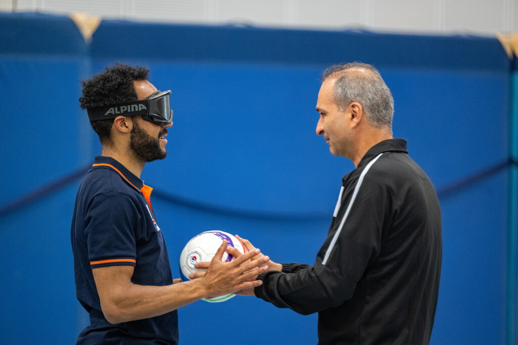 geblindeerde sporter krijgt de bal in zijn handen van een trainer