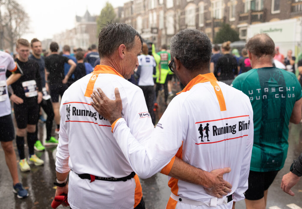 Twee Running Blind finishers met de armen op elkaars rug om elkaar te feliciteren.