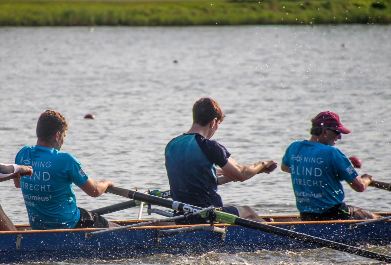 drie roeiers in een roeiboot
