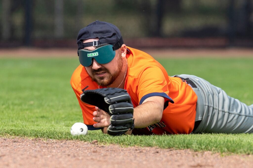 blind baseballspeler rick duikt naar de bal op de grond