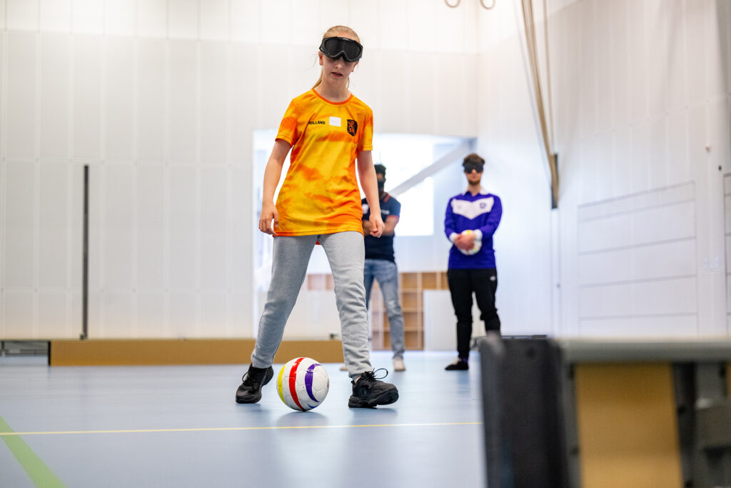 sporter in oranje shirt oefent met de bal in een sportzaal
