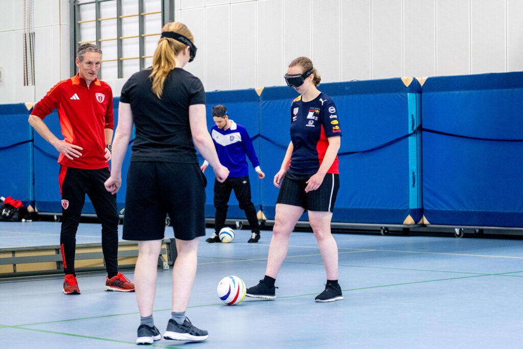 sporters oefenen blindenvoetbal in een sportzaal