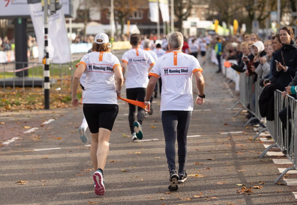 twee hardlopers tijdens een hardloopwedstrijd: een slechtziende loper met een buddy