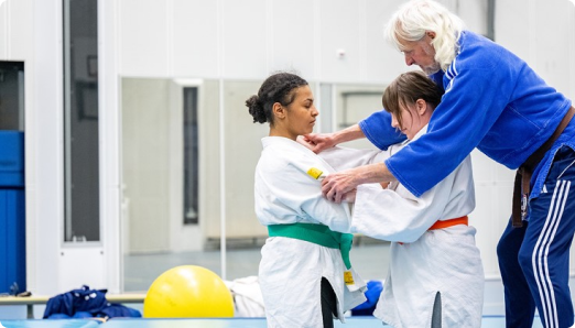 Trainer, buddy en sporter leren samen judo.
