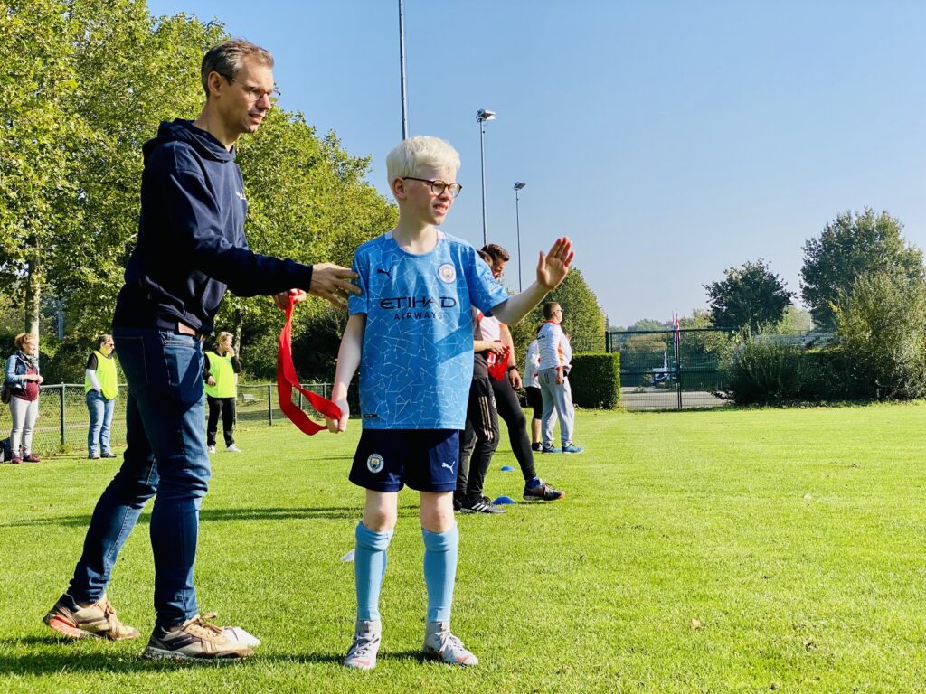 Man die een jongen een instructie geeft voor running blind op een grasveld.