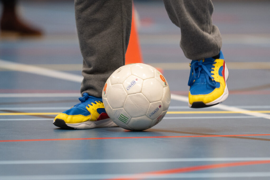 Rinkelbal met twee voeten die de bal controleren in een sportzaal.