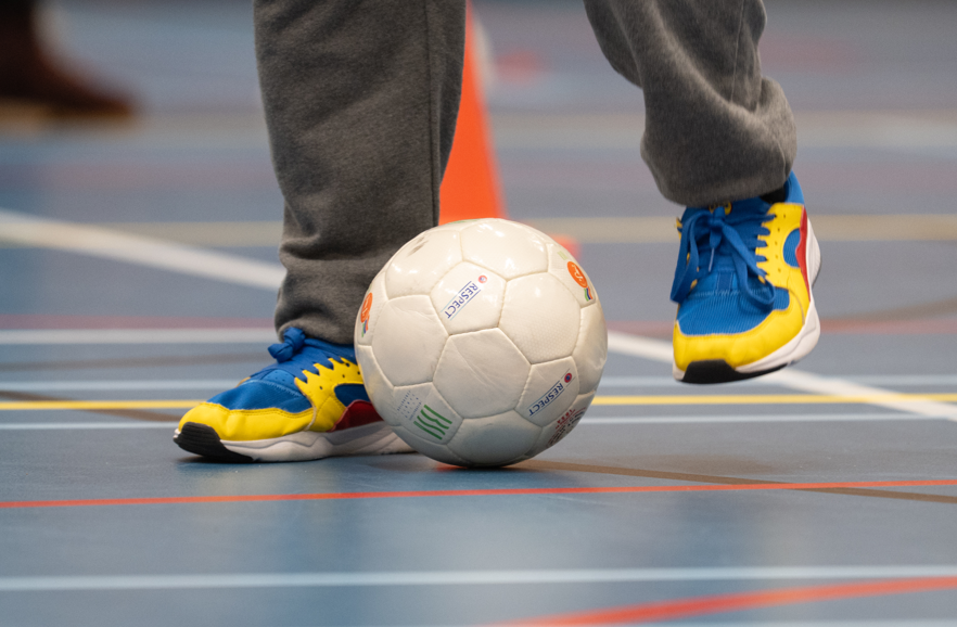 voetbal en twee voeten van iemand die voetbal speelt in een sportzaal