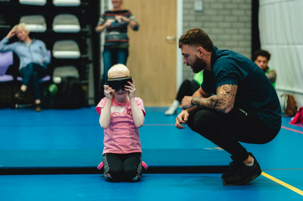 coach hurkt naast een sporter die een geblindeerde bril draagt